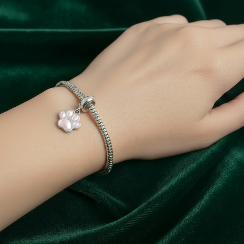 Silver bracelet with pandora ashes paw print charm on a textured fabric background