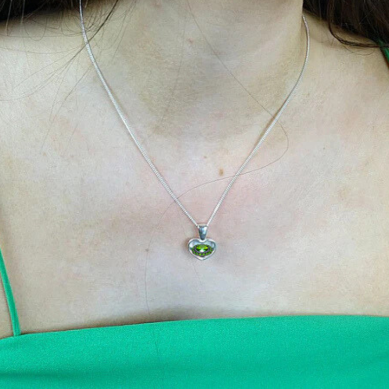 small heart shaped peridot ashes memorial necklace on a model