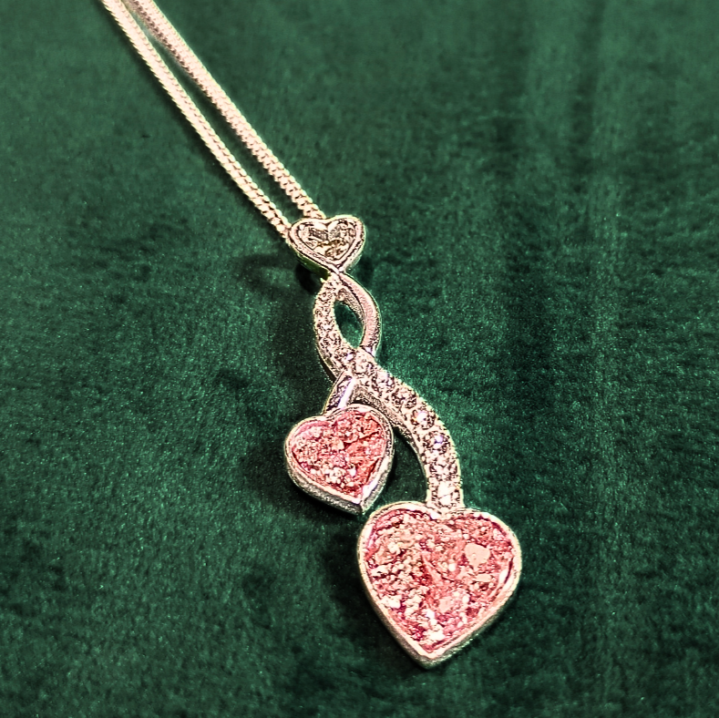 two hearts entwined ashes necklace on green velvet background in pink topaz colour