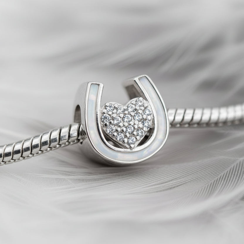 Silver bracelet with an ashes horseshoe pandora charm featuring a heart design on a white background