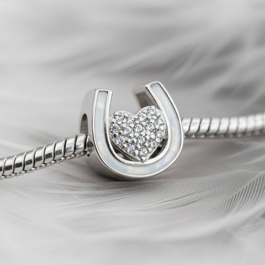 Silver bracelet with an ashes horseshoe pandora charm featuring a heart design on a white background