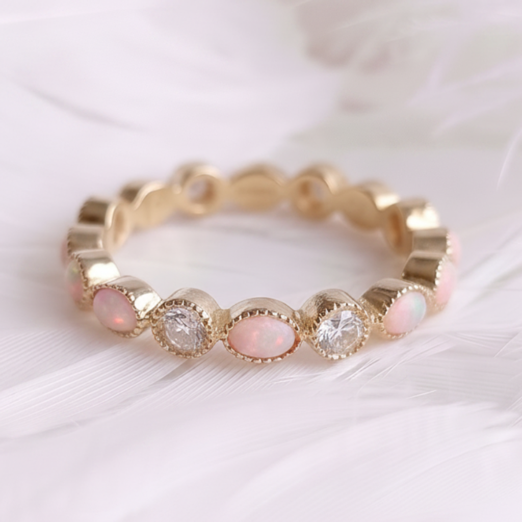 A 14ct or 18ct gold ashes eternity ring featuring marquis pink opal ashes stones and genuine natural diamonds, displayed on a soft white feather background.