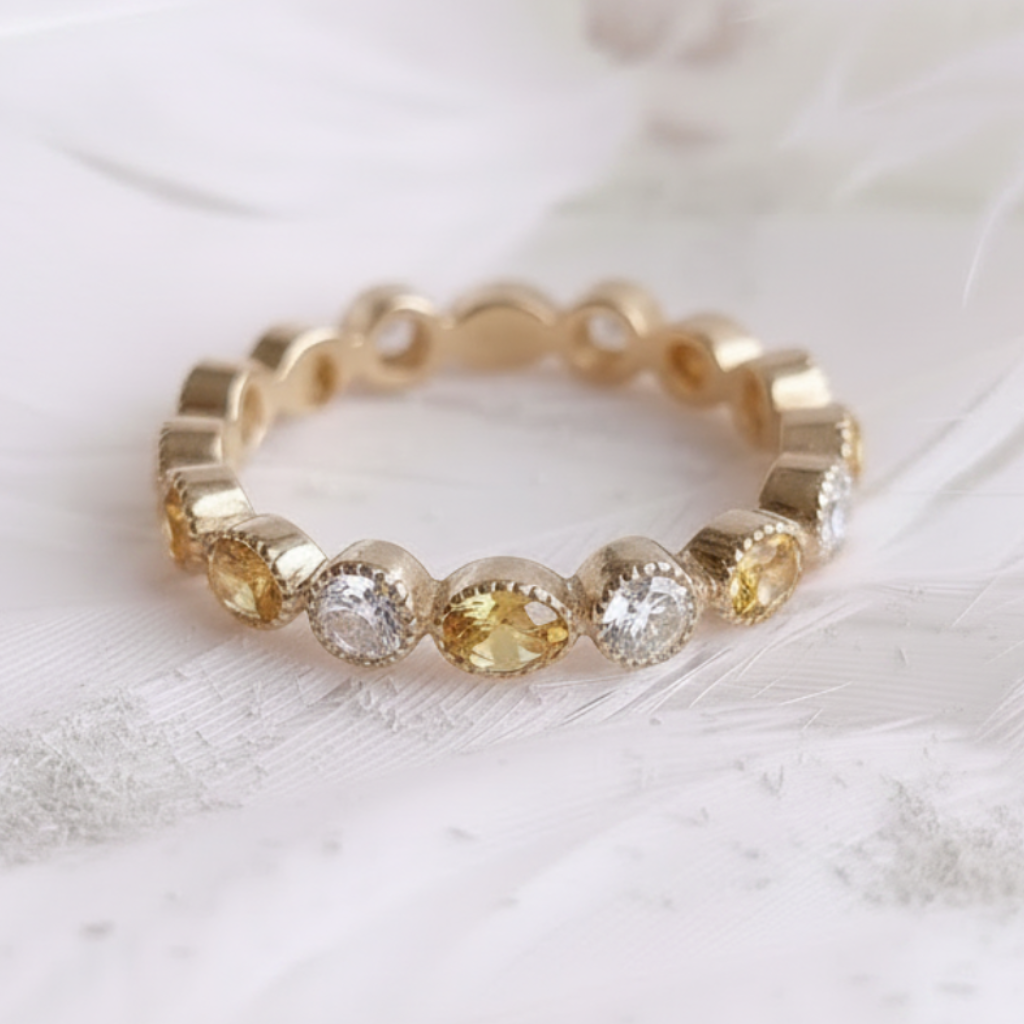14ct or 18ct gold ashes ring featuring citrine ashes stones with real diamonds, resting on a soft white feather background.