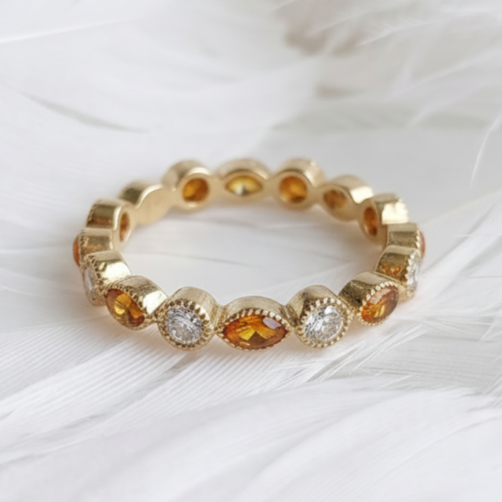 14ct or 18ct gold ashes eternity ring with amber ashes stones and real diamonds, displayed on a bed of soft white feathers. 