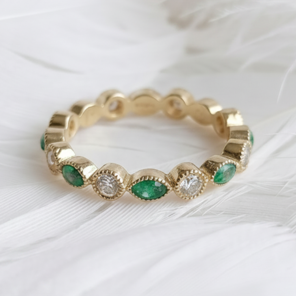 14ct or 18ct gold ashes eternity ring with emerald ashes stones and genuine diamonds, displayed on a bed of soft white feathers.