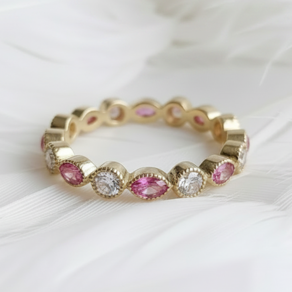 14ct or 18ct gold ashes eternity ring with pink topaz ashes stones and genuine diamonds, displayed on a bed of soft white feathers.