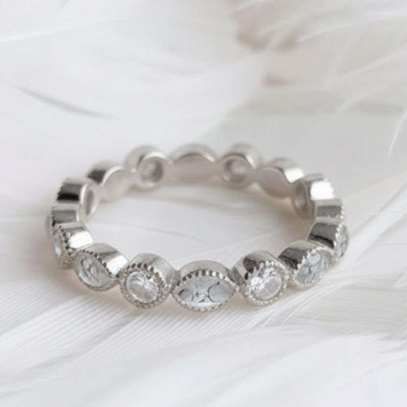 A silver ashes eternity ring featuring marquis diamond natural ashes stones displayed on a soft white feather background.