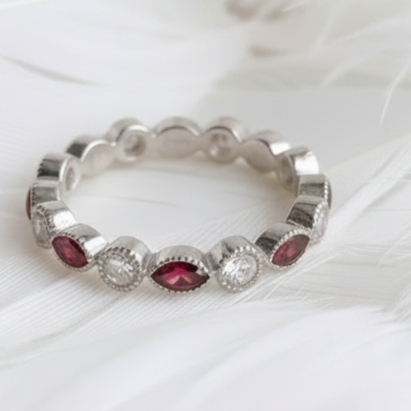 A silver eternity ashes ring featuring garnet ashes stones, displayed on a soft white feather background.