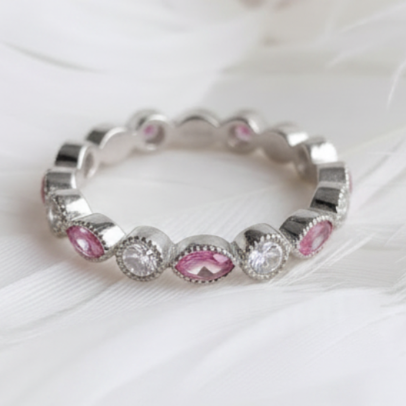 A silver eternity ashes ring featuring garnet ashes stone displayed on a soft white feather background.