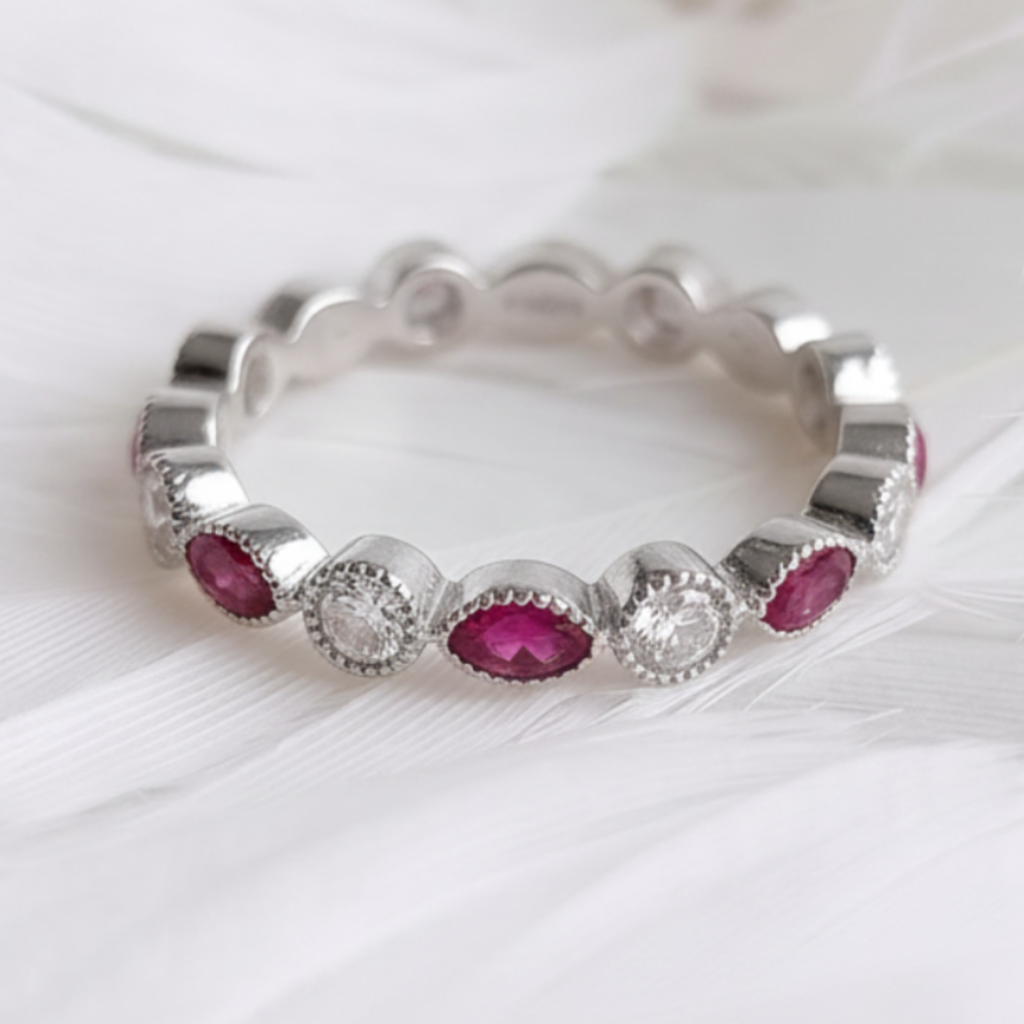 A silver eternity ashes ring featuring small marquis ashes stones and clear round cubic zirconia stones, displayed on a soft white feather background.