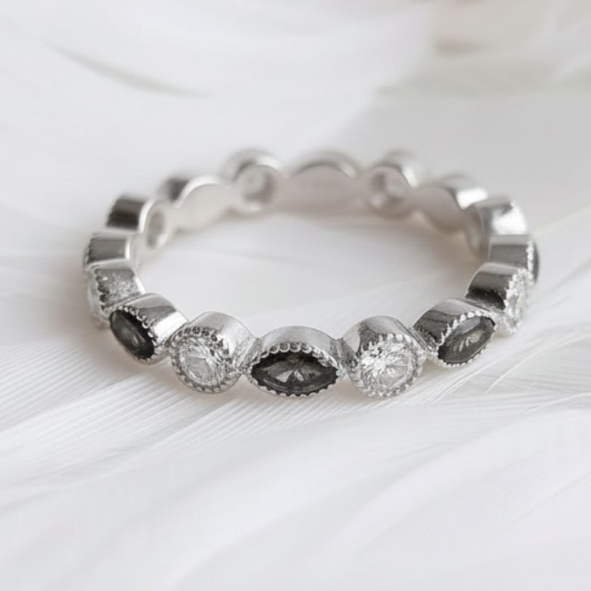 A silver ashes eternity ring featuring onyx ashes stones clear cubic zirconia stones, displayed on a soft white feather background.