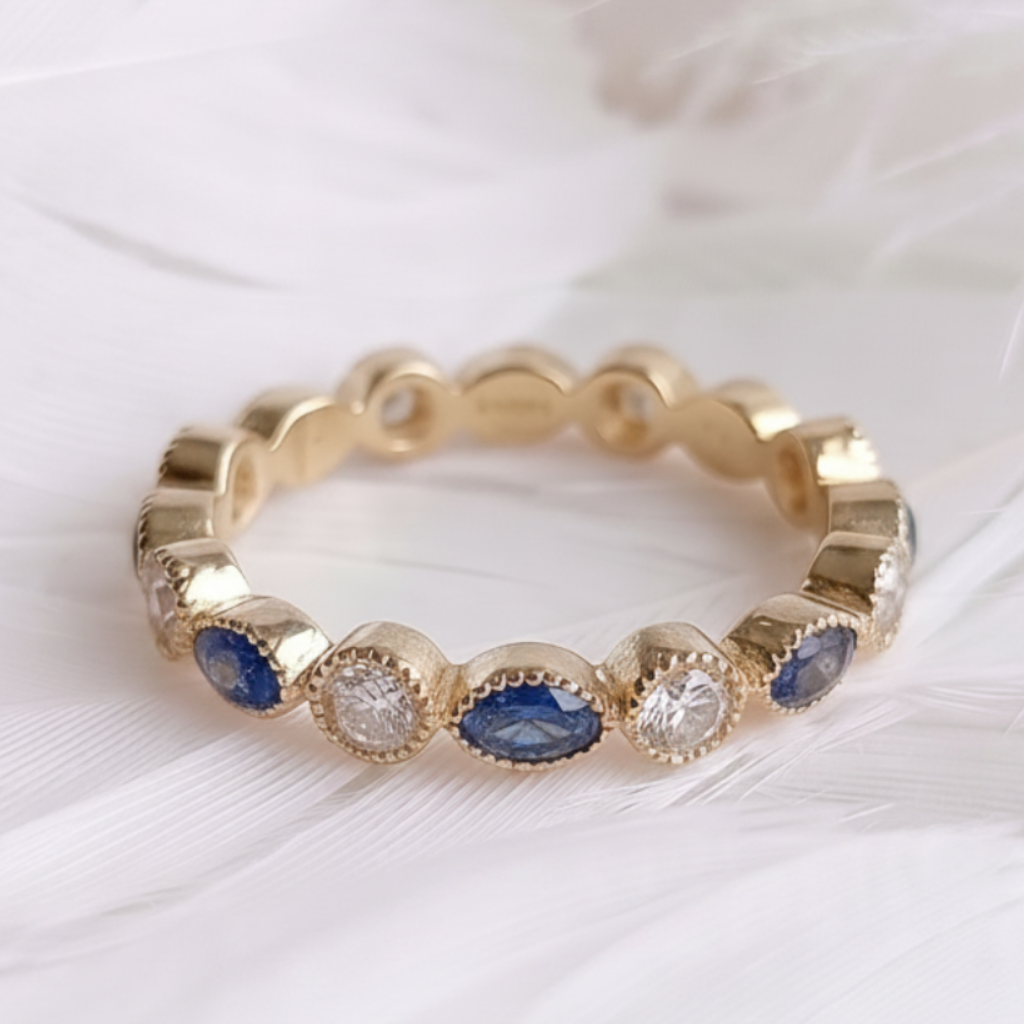 A 14ct 18ct gold ashes eternity ring featuring marquis sapphire ashes stone and genuine diamonds, displayed on a soft white feather background.