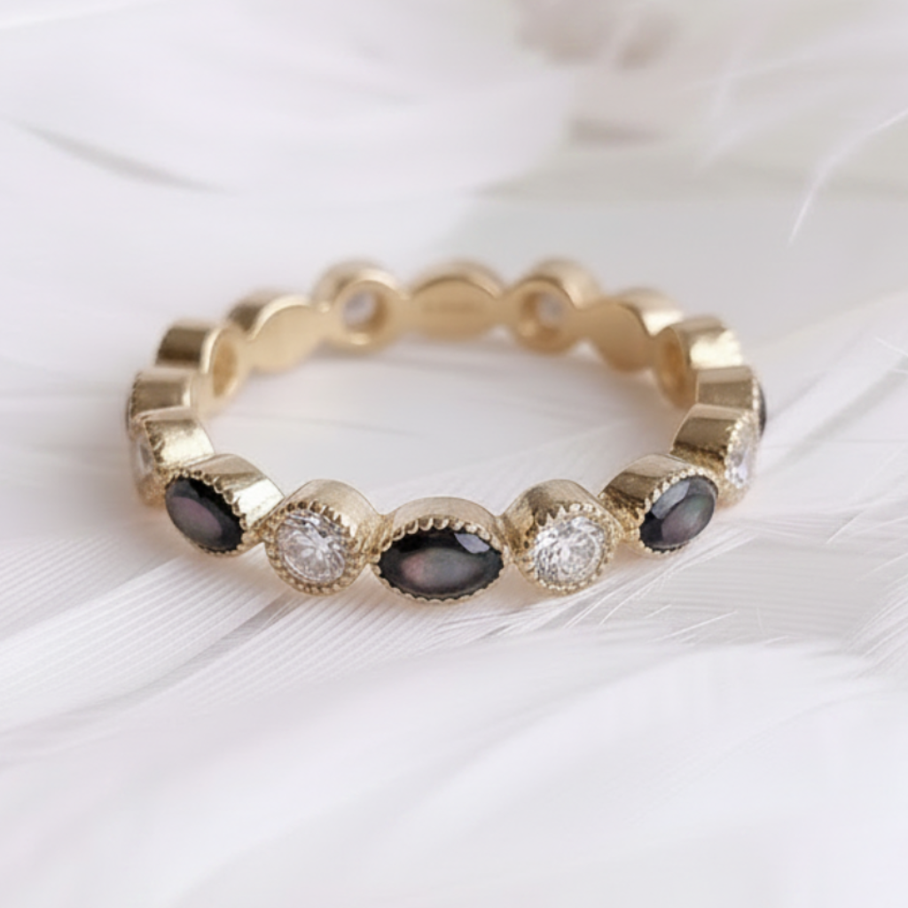 14ct or 18ct gold ashes eternity ring featuring black pearl ashes stones and genuine diamonds, displayed on a soft white feather background.