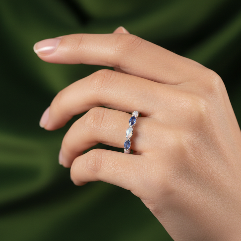 marquis ashes birthstone ring on a hand with green backdrop