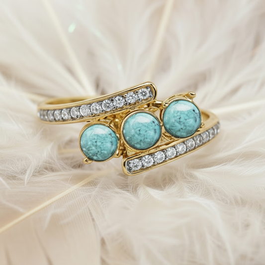 14ct yellow gold trilogy ashes ring set with turquoise memorial stones, on feather background